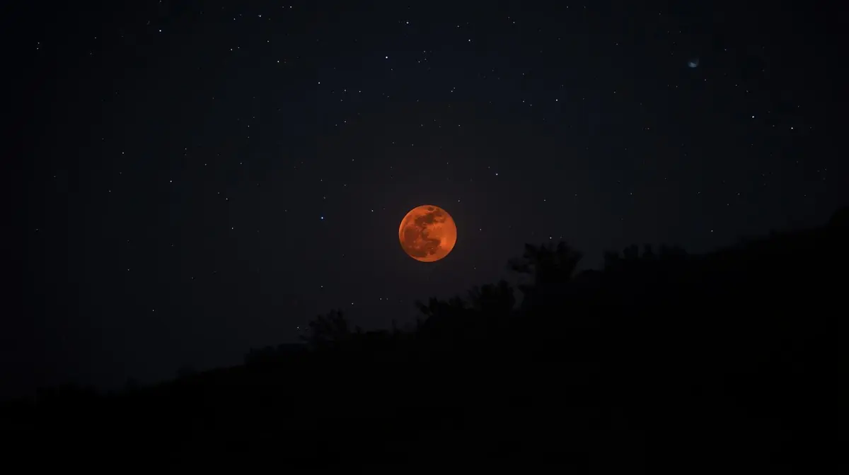A deep copper-red full moon against a dark night sky, photographed during a total lunar eclipse